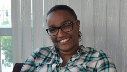 Person smiling with blinds in background.