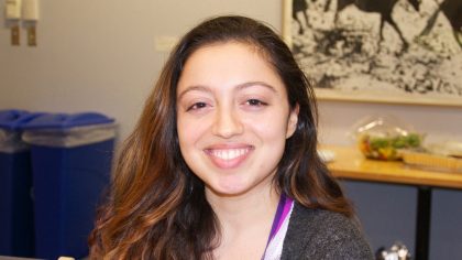 Person smiling with painting in background.