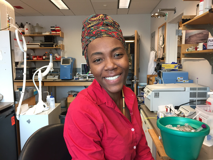 Person smiling with lab equipment in background.