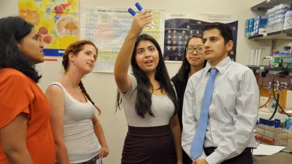 Group of five students looking at test tubes