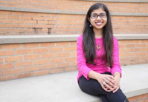 Person with long hair and glasses sitting on steps