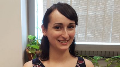 Person with brown hair smiling by window