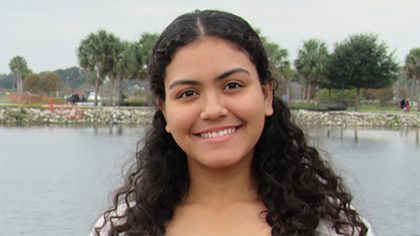 Person with long hair smiles outside