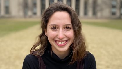 Person with long, brown hair standing in front of MIT dome