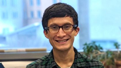 Man with short hair and glasses smiling in lab