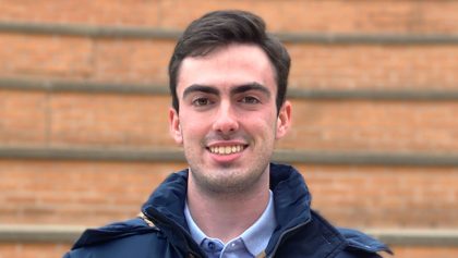 Man smiling in front of bricks