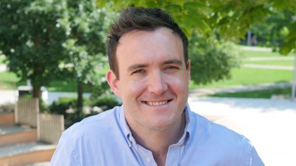 Man with short hair smiling outside