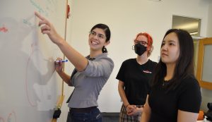 three people at a whiteboard